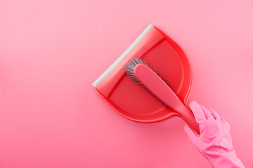 Hand in pink rubber glove holding dustpan and brush - obrazy, fototapety, plakaty