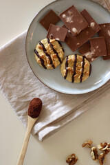 Cup of tea or coffee, cookies, macaroons, chocolate, various nuts and cocoa powder on white background. Top view.