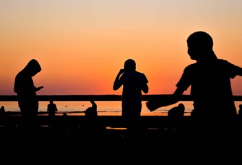 Silhouettes of people having a good time on the beach with beautiful sunset in the background. 