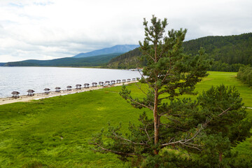 Summer landscape of Lake Baikal. Equipped tourist recreation areas with a table on the lake shore, camping places. Chivyrkuysky Bay, Republic of Buryatia. 