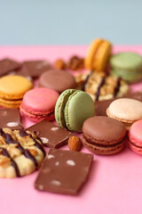 Pastel macarons, almond chocolate, peanut butter cookies and various nuts on bright pink background. Selective focus.