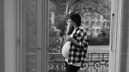 Expectant Mother Relishing Quiet Tea Time on Urban Balcony, Serene Cityscape in Pregnancy's Late Stage in black and white