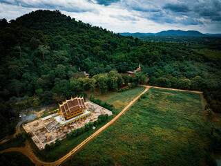 Chachoengsao, Thailand, 28 July 2023. Wat Khao Tham Raet, Aerial view of a temple complex in the middle of a lush green forest. 