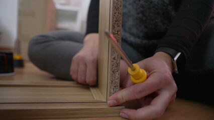 Close-up hand putting together furniture, DIY setup. Person placing two pieces of wood together....