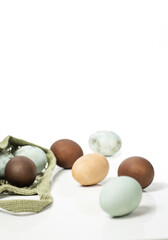 many chicken eggs for Easter, painted brown, blue and marbled on a white background.