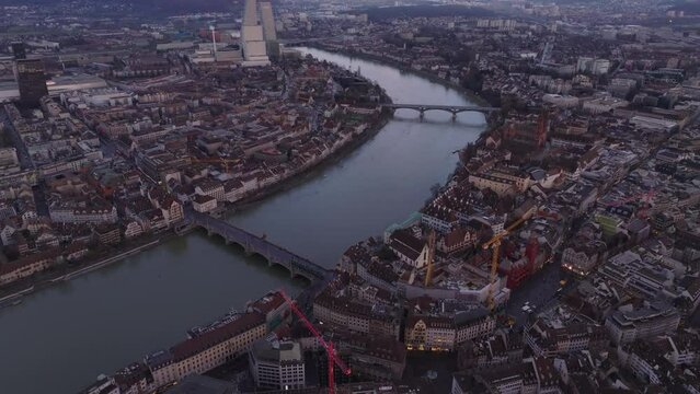 High angle view of historic buildings and bridge in old town. Tilt up reveal cityscape at dusk. Basel, Switzerland