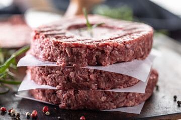 Fresh raw ground beef patties with rosemary salt and pepper made in a meat form on a cutting board - 786375578