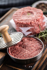 Fresh raw ground beef patties with rosemary salt and pepper made in a meat form on a cutting board - 786375723