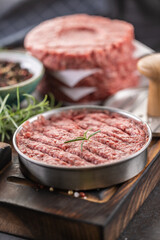 Fresh raw ground beef patties with rosemary salt and pepper made in a meat form on a cutting board - 786375995