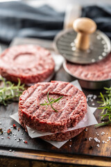 Fresh raw ground beef patties with rosemary salt and pepper made in a meat form on a cutting board - 786376116