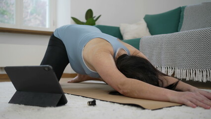 Pregnant woman stretching body in while on Yoga man at living room floor. expectant mother taking...
