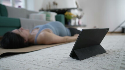 Pregnant woman practicing daily workout routine at home in front of table device at living room...