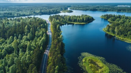 Aerial view of road in green woods and blue lakes water in summer Finland 