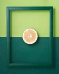Pomelo in picture frame on two-tone green background