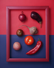 Red vegetables in wooden frame on red and blue