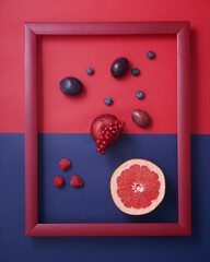 Red fruits and berries in  frame on red and blue