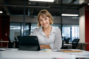 Happy young caucasian businesswoman smiling while using digital tablet during meeting in office - 786384383