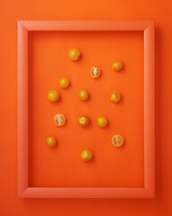 Cherry tomatoes in picture frame on orange background