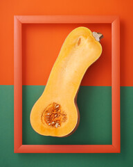 Pumpkin in picture frame on orange and green background