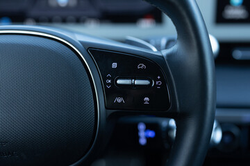 Close up of steering wheel of a new electric vehicle. Electric car control devices. Cruise control...