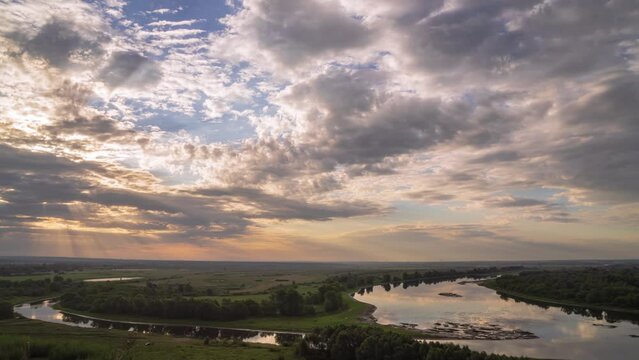 Beautiful morning landscape with summer forest and river. Time lapse sunrise over river. Beautiful sky with rolling clouds. Water surface in fast motion.