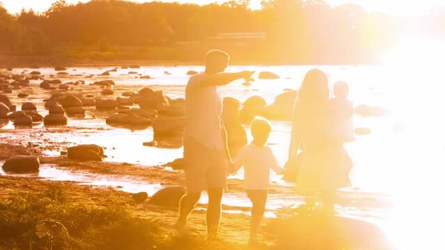 Happy family near the sea. Field and trees in countryside. Warm colors of sunset or sunrise. Loving parents and beautiful children. The concept of love and parenthood.
