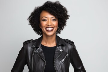 Portrait of a happy afro-american woman in her 40s sporting a classic leather jacket while standing against white background