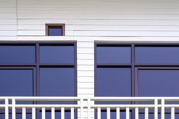 Glass doors on white artificial wooden wall with steel balustrade on balcony of vintage 2 storey house