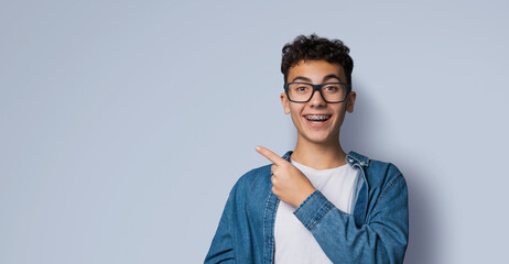 Excited happy black curly haired man in braces, open mouth, wear glasses denim shirt advertise show...