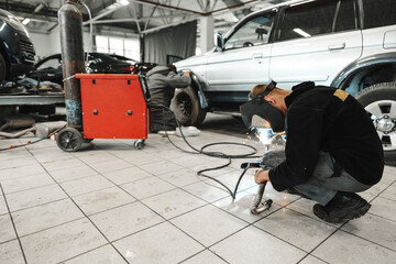 Welder in mask repairing detail in car service