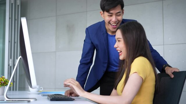 Excited young Asian startup business team celebrate successful and victory and hand up at office and looking at camera, happy euphoric proud Asian male and female professional winner feel overjoyed