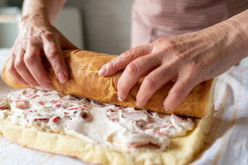 Making a cake roulade or swiss roll. Rolling up a cake with filling