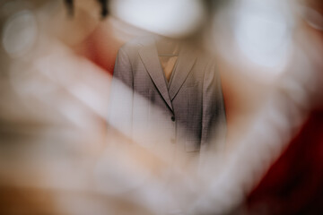 Valmiera, Latvia- July 28, 2024 - A grey suit jacket hangs in focus behind a blurred white veil.