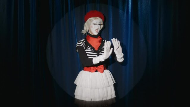 Female mime artist performing improvised comedy show in spotlight on theatre stage