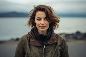 Portrait of a merry woman in her 40s wearing a trendy bomber jacket on tranquil ocean backdrop