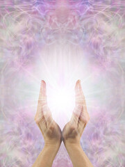 Reiki Healer using the Power of Intention to send healing energy - Female hands with white starlight  between against a beautiful pink and spiritual ethereal background with space for text - 786406501