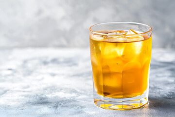 Chilled kombucha tea with ice cubes on light grey background, copy space. Cold kombucha drink in a glass. Iced kombucha beverage, refreshing golden drink. Fermented tea kvass