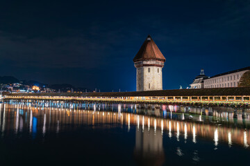 Chapel Bridge over river Reuss in Luzern, Switzerland at night with bright, colorful lights