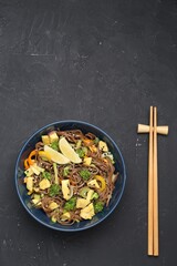 Stir-fry. Delicious cooked noodles with chicken and vegetables in bowl served on gray textured table, space for text