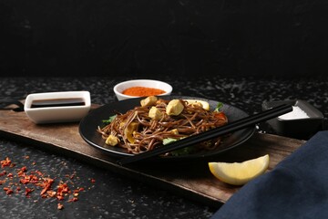 Stir-fry. Tasty noodles with vegetables and meat served on dark textured table