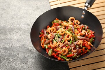 Shrimp stir fry with vegetables in wok on grey table