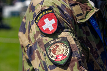 Naklejka premium Close-up of coat of arms and badges on uniform of Swiss soldier at military training area at City of Bülach on a sunny summer day. Photo taken August 18th, 2023, Bülach, Canton Zürich, Switzerland.