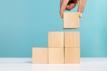 Concept for business growth or success process. Hand put last piece of wooden cube stacking as step...