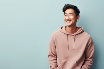 Portrait of a happy asian man in his 20s dressed in a comfy fleece pullover in modern minimalist interior