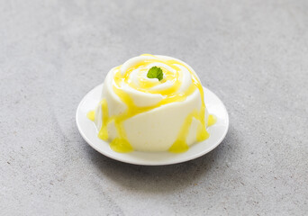 Vegan dessert. Lemon cream pudding, Panna Cotta in the shape of a rose, with lemon sauce. Light grey background. Close-up
