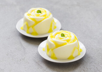 Vegan dessert. Lemon cream Panna Cotta in the shape of a rose, with lemon sauce. Light grey background. Close-up