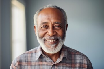 Obraz premium Portrait of a smiling afro-american elderly man in his 90s dressed in a relaxed flannel shirt over modern minimalist interior