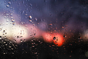 a view from inside of a rain covered window at sunset