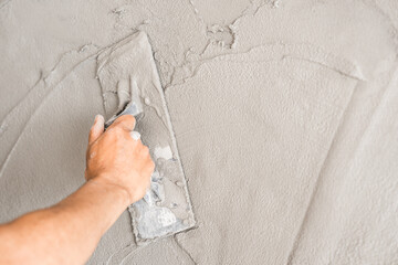 Hand plasterer plastering trowel wet cement house wall background  