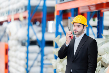 half body photo European male engineer having a meeting with factory owner and customers with radio in hand, working in plastic and steel manufacturing industry. Wear a safety helmet and suit.